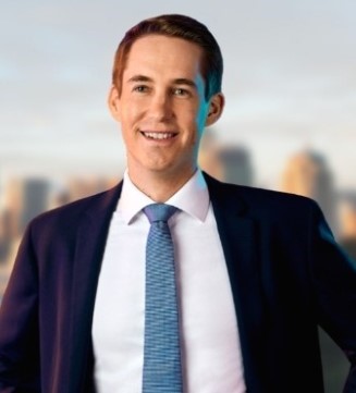 Headshot of Andreas Heger, with blurred background imagery of a cityscape.